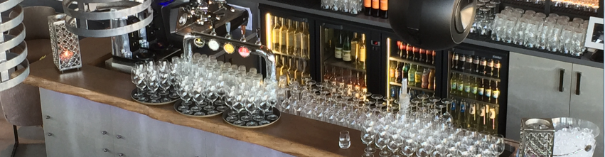 Bar lined with glasses and bottle coolers behind.