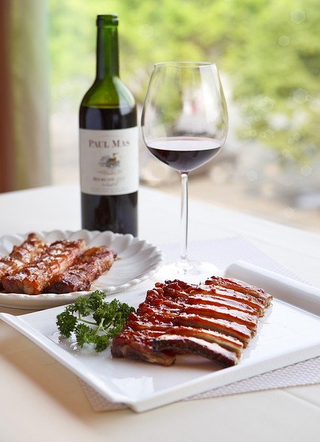 Bottle of wine, red wine in glass and rack of ribs