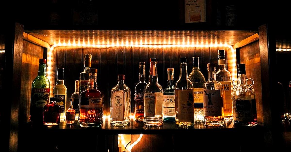 back bar display of spirit bottles in front of a mirror surrounding by lights