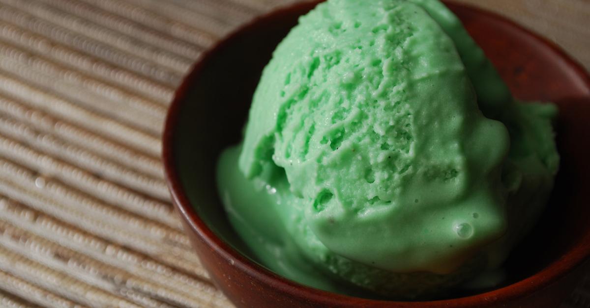 green ice cream in a bowl on wooden table