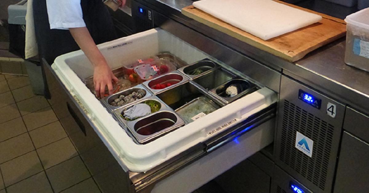 chef putting food into an open refrigerated chefs drawer filled with gastronorm pans of ingredients