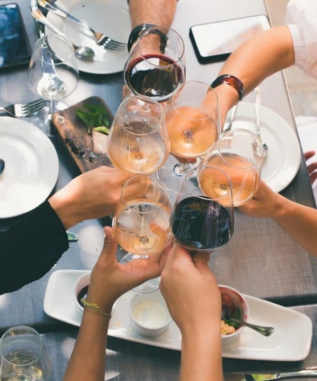 wine glasses being toasting by people over a table